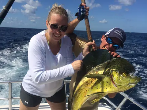 Angler and mate holding a bull mahi-mahi on an offshore fishing charter