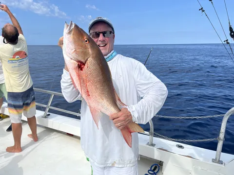 Angler holding a mutton snapper on an offshore charter