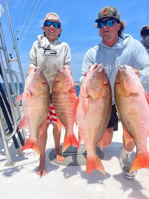 Two anglers holding four mutton snapper caught sport fishing off St. Augustine, FL