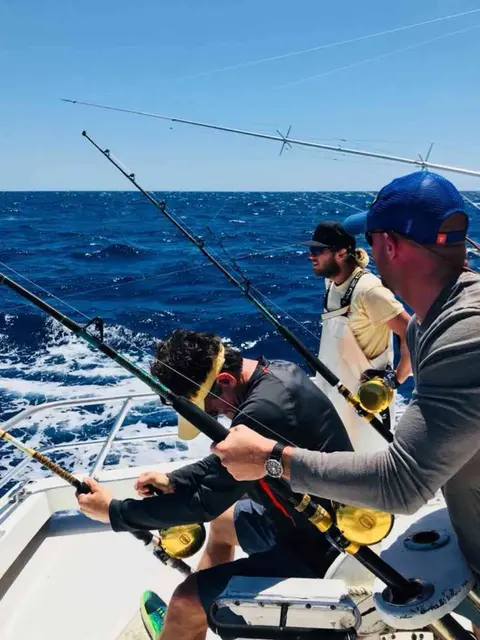 Anglers reeling in fish at the stern while the mate stands by