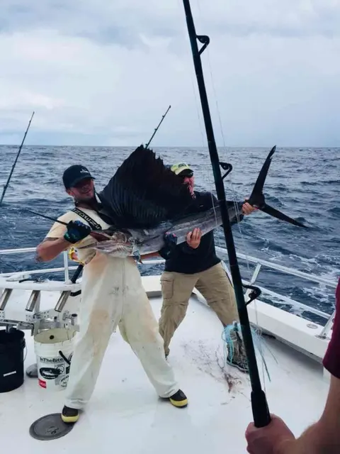 Anglers holding a sailfish on the deck offshore of Jacksonville Beach, FL