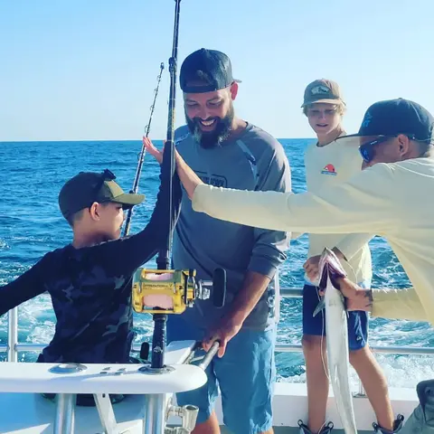 Family with kids landing a catch together on a fishing charter getaway in St. Augustine, FL