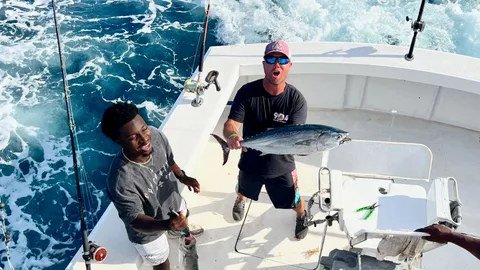Angler holding a blackfin tuna in the cockpit of an offshore charter boat